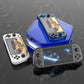 Three handheld gaming consoles on a reflective black surface
