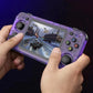 Hand holding a purple gaming device with a racing game on screen against a dark background
